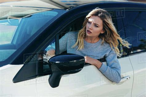 Young Shocked Woman Leaning Out Car Window While Driving Car Stock