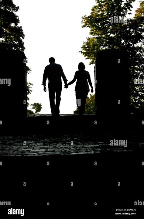 Silhouette Of A Man And Woman Walking Away As A Couple Hand In Hand