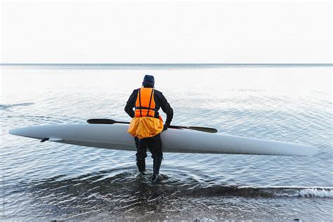 Man Carrying Kayak Into The Sea By Stocksy Contributor Lior Lone