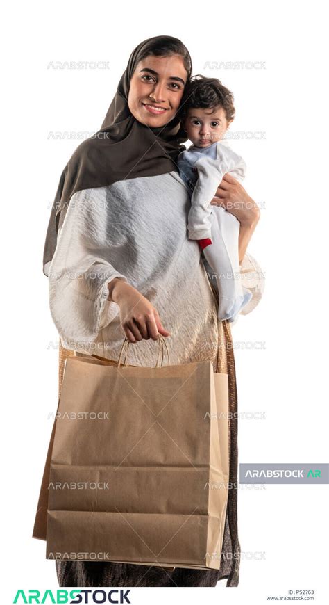 بورتريه لأم عربية خليجية سعودية تحمل طفلها الرضيع بسعادة وحنان، وبيدها حقائب التسوق، الاستمتاع