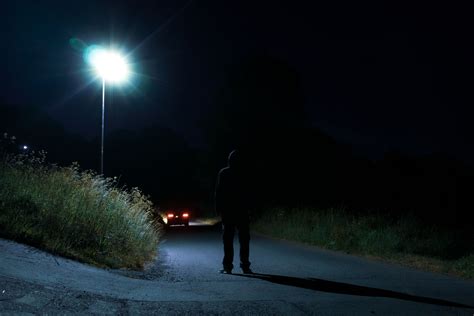 A Mysterious Hooded Figure Standing Under A Street Light By Stocksy