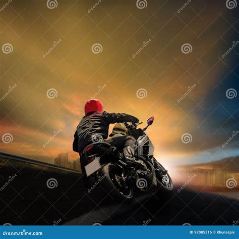Man Riding Motorcycle on Asphalt Highway Against Sunset Sky Stock Photo