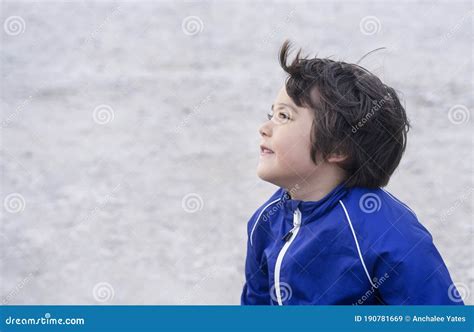 Side View Portrait Of Cute Little Boy Sitting Alone With Blurry Sand