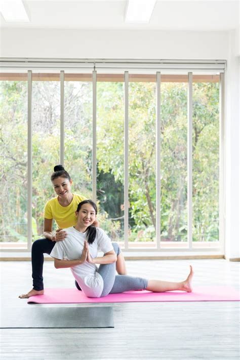 Two Happy Asian Women In Yoga Poses In Yoga Studio With Natural Light