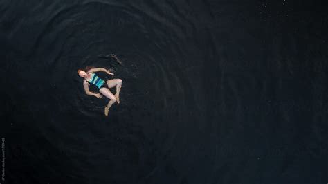 aerial photo of woman playfully swimming in dark freshwater cottage lake del colaborador de