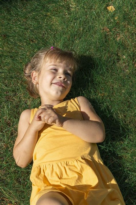 Portrait Of Smiling Little Girl Lying On Green Grass Stock Photo