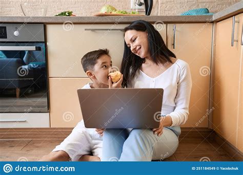 Kid Biting Apple While Working With Laptop Near Mother Stock Image