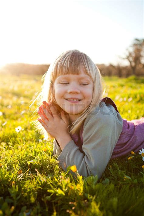 Nettes kleines Mädchen im Freien auf der grünen Wiese mit Blumen