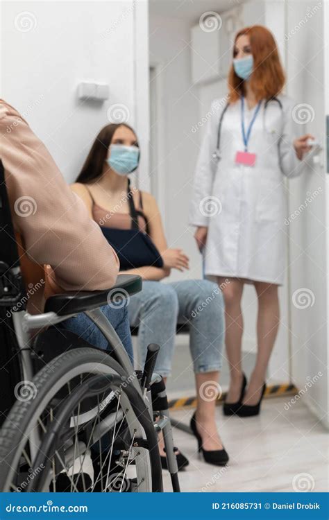 In The Foreground A Wheelchair And In The Background A Redheaded Doctor