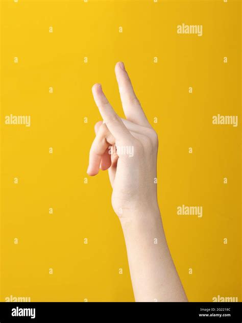 Teen Hand With Two Fingers Up Shows Goat Gesture On Yellow Background