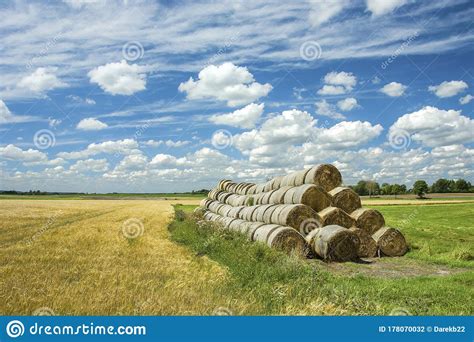 Stack Of Hay Bales And Meadow Horizon And White Clouds On A Blue Sky