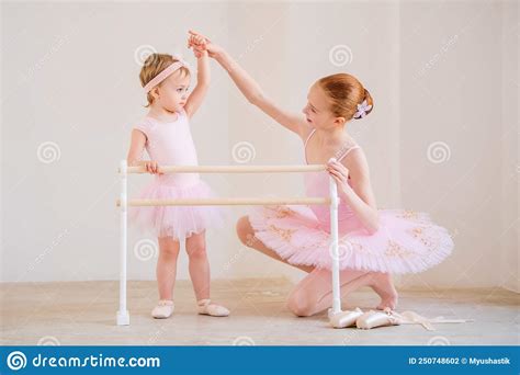 The Older Sister A Ballerina In A Pink Tutu And Pointe Shoes Shows