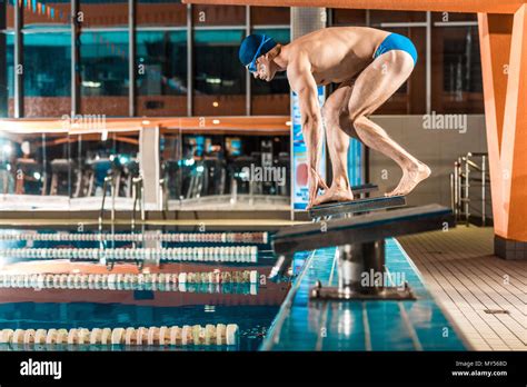 Swimmer Standing On Diving Board Ready To Jump Into Competition