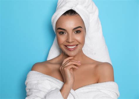 Beautiful Young Woman Wearing Bathrobe And Towel On Head Against Light Blue Background Stock