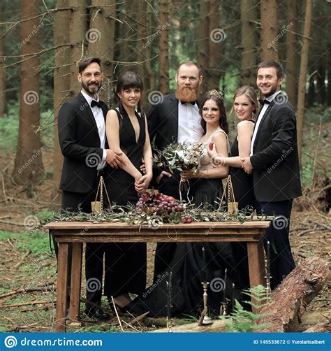 Guests And A Couple Of Newlyweds Near The Picnic Table In The Woods
