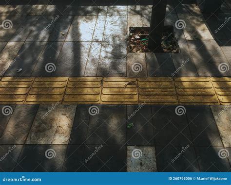 Yellow Pedestrian Path For The Disabled On A Sidewalk Stock Photo