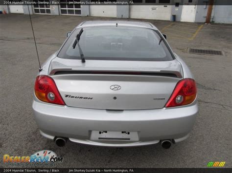 The tuscani wears a circular badge containing a smaller circle of black and grey horizontal bars which is overlaid with a letter 't' painted gold on the left and silver on the right. 2004 Hyundai Tiburon Sterling / Black Photo #4 ...