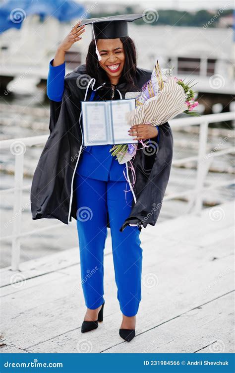African American Student Girl In Black Graduation Gown With Diploma At