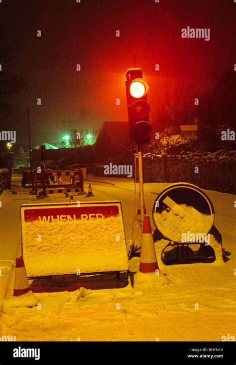 Red Traffic Light At Roadworks In In Winter Snow At Night Near Leeds
