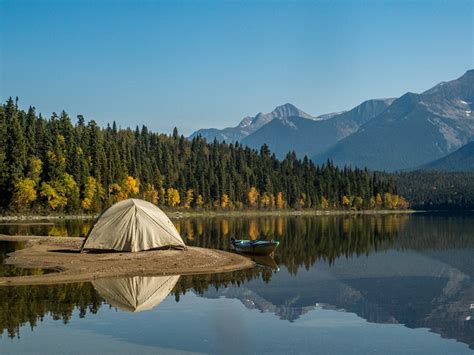 White Tent On Lake Near Green Trees And Mountain Under Blue Sky During