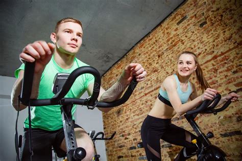 Cycling On Exercise Bikes Three Attractive Young Women In Sports Clothing Exercising On Gym