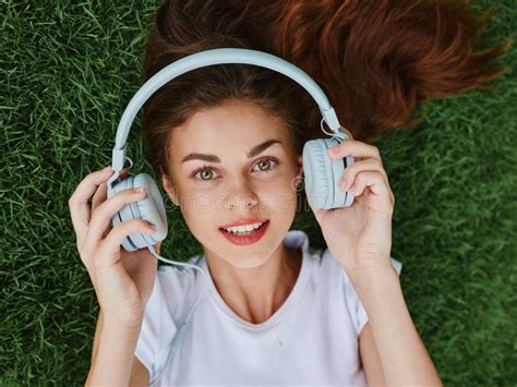 Beautiful Woman Wearing Headphones Listening To Music Lying On The