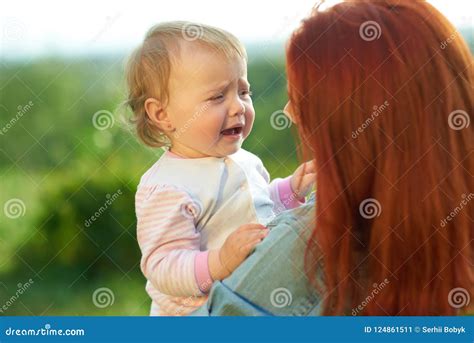 Crying Daughter Sitting On Mother S Hands During Sunny Day In The Field