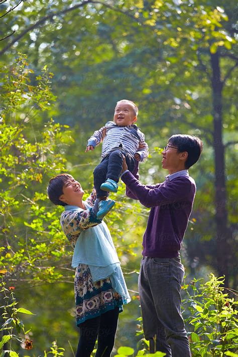 Happy Parents Holding Their Little Boy Up In The Park By Stocksy