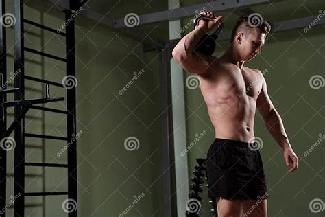 ein muskulöser kerl mit einem nackten torso hat ein gewicht auf seiner schulter und beugt sich