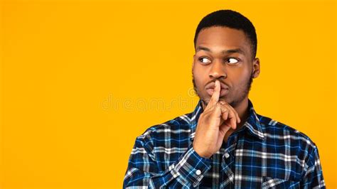 Black Guy Putting Finger On Lips Posing Over Yellow Background Stock