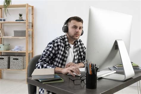 Young Man In Headphones Using Modern Computer For Studying At Home
