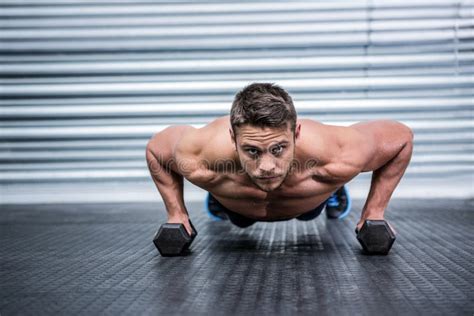 Portrait Of Muscular Man Doing Push Ups With Dumbbells Stock Photo