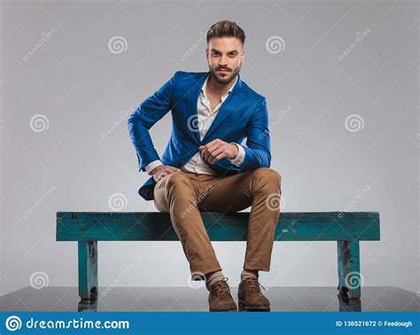 Handsome Smart Casual Man Sitting On Bench Leans Forward Stock Photo
