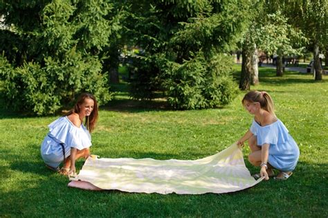 premium photo two girls on a green meadow spread out a picnic blanket