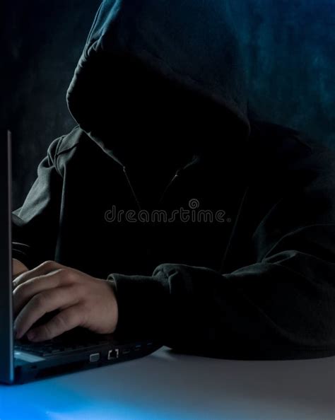 Anonymous Computer Hacker In Hoodie Using Laptop Computer For Cyber