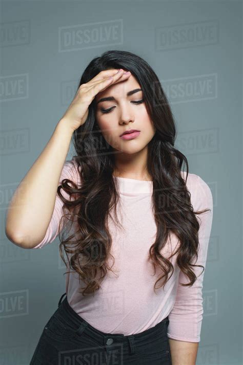 Brunette Woman Suffering From Headache Isolated On Grey Stock Photo