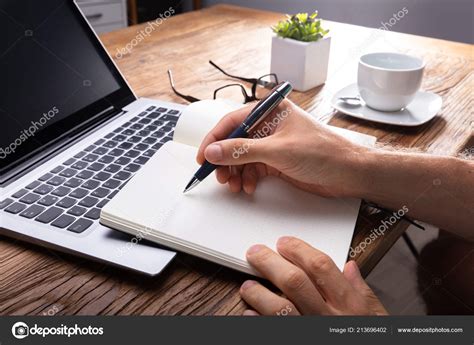 Persons Hand Writing Black Notebook Using Pen Laptop Stock Photo By