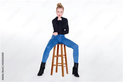 Sexy Girl In Tight Jeans Sitting On Stool With Legs Apart And Chin
