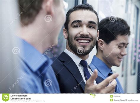 Three Businessmen Standing In A Row And Talking On The Subway Stock