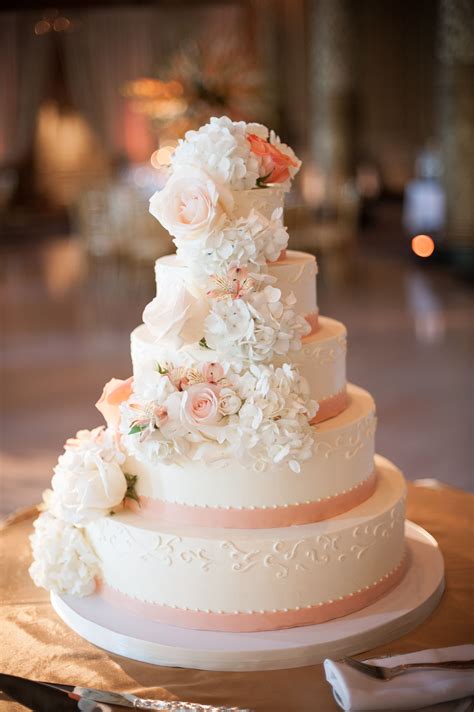White Wedding Cake With Peach Ribbon And Cascading Flowers