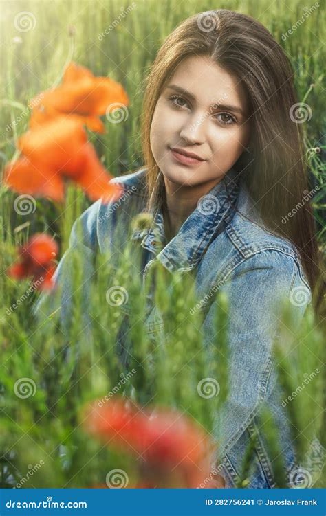 Portrait Of Attractive Long Haired Girl From Behind Red Poppy Leaves