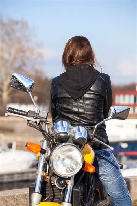 rear view at sexy woman sitting on motorcycle in black leather pants ass with back view stock