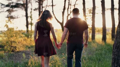 Young Couple Walk In Forest At Beautiful Sunset Sun Rays Shine Lovers