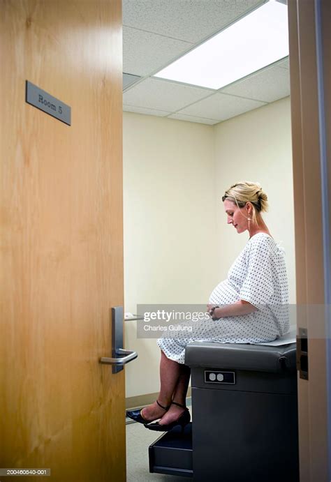 Pregnant Woman Sitting On Exam Table In Doctors Office High Res Stock
