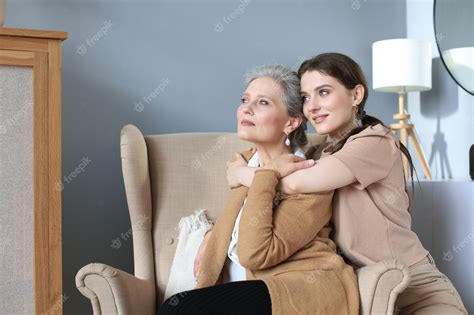Premium Photo Happy Daughter Hugging Older Mother Standing Behind Chair In Living Room