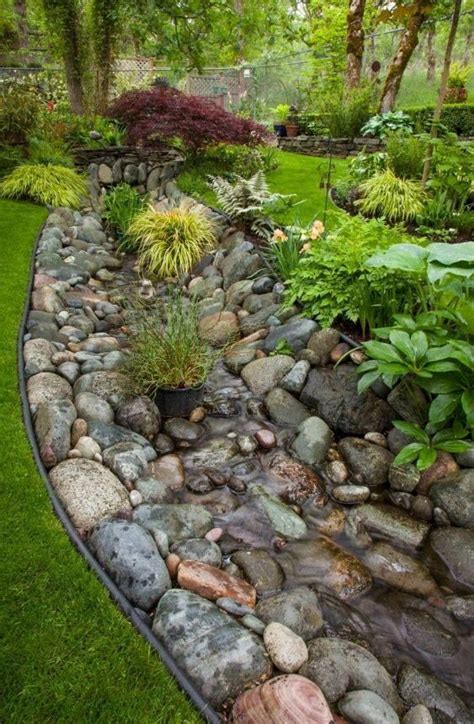 A french drain is ideal for carrying away surface water which builds up around walls, on french drain detail showing a cross section showing the graded stones and a perforated drainage pipe. natural french drain boulders - Nature's Earth Products