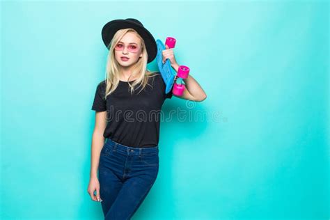 Portrait Of Blonde Woman In Sunglasses Posing With Skateboard While Standing And Looking At