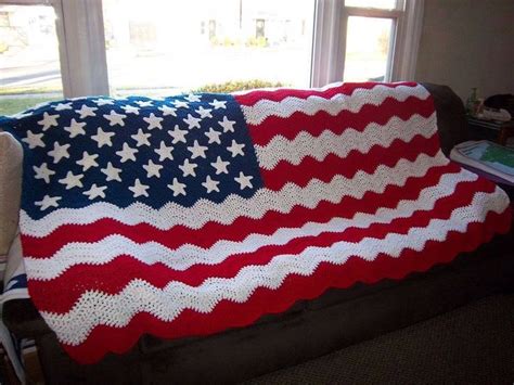 An American Flag Crocheted Afghan On A Couch In Front Of A Large Window