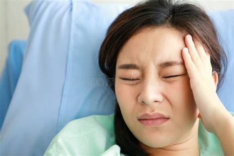 Asian Young Long Hair Sick Ill Girl Patient Wears Green Hospital Uniform Lay Down On Bed Hold