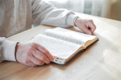 Senior Man Praying Reading An Old Bible In His Hands Stock Photo